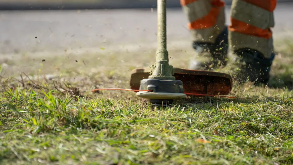 Close-up of a line trimmer defining a crisp edge for high-end lawn care finishes.